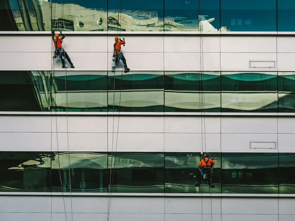 A technician washing the exterior of a white commercial building