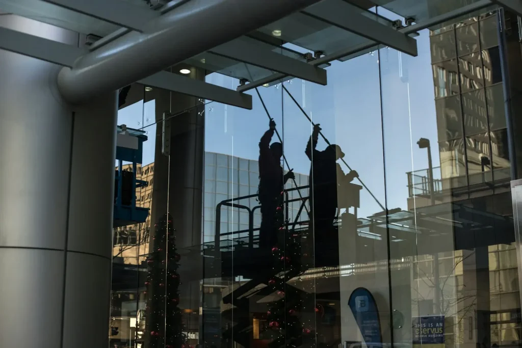A window cleaning technician on a lift platform cleaning commercial glass