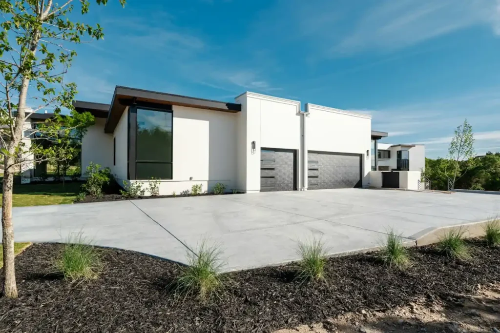 A modern white home with two garage doors and a freshly cleaned concrete driveway