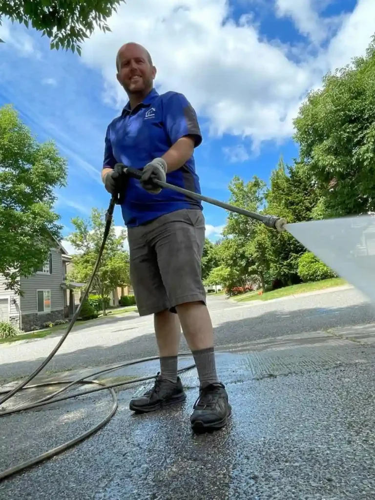 A technician pressure washing a residential concrete driveway in Indianapolis