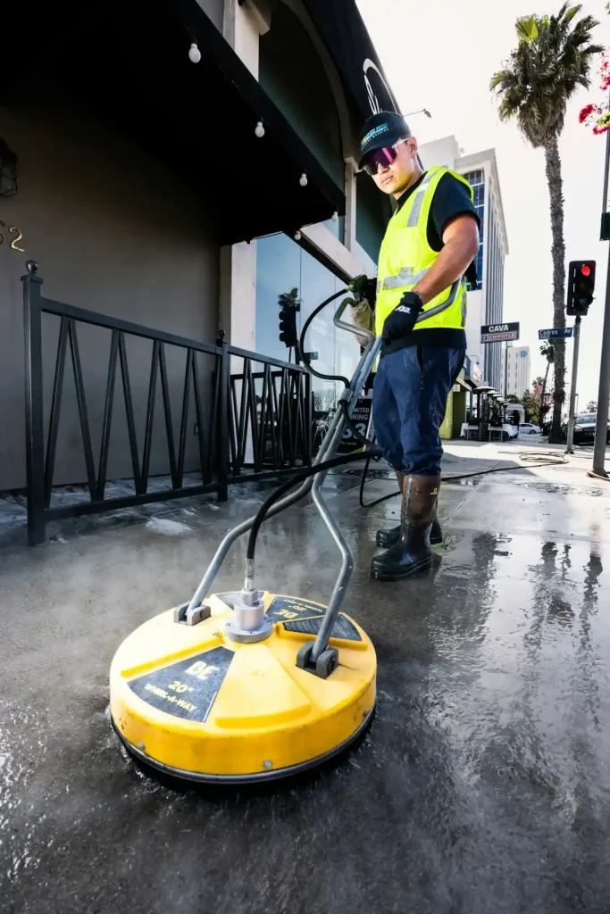 Crew member pressure washing a commercial hard surface area