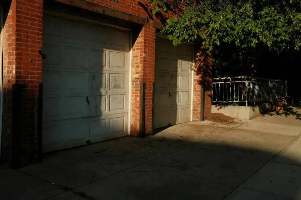 Sunlight across two clean white garage doors and a washed concrete apron