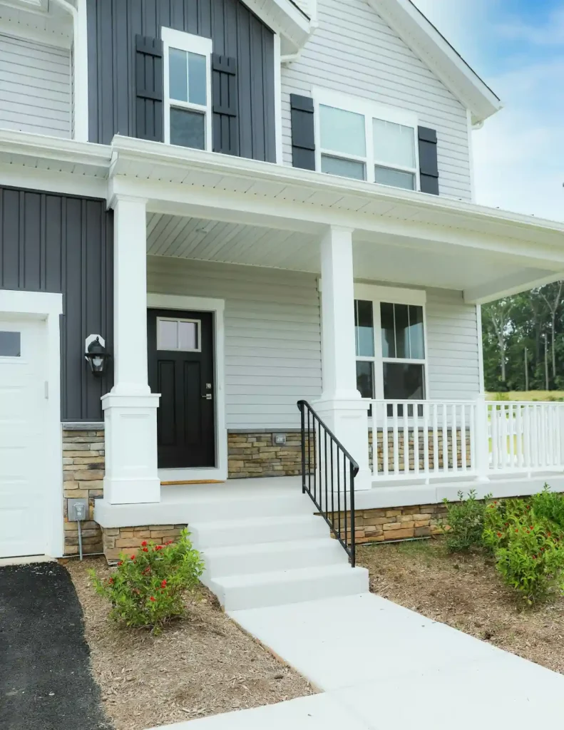 A white sided home with a black front door after a professional soft wash