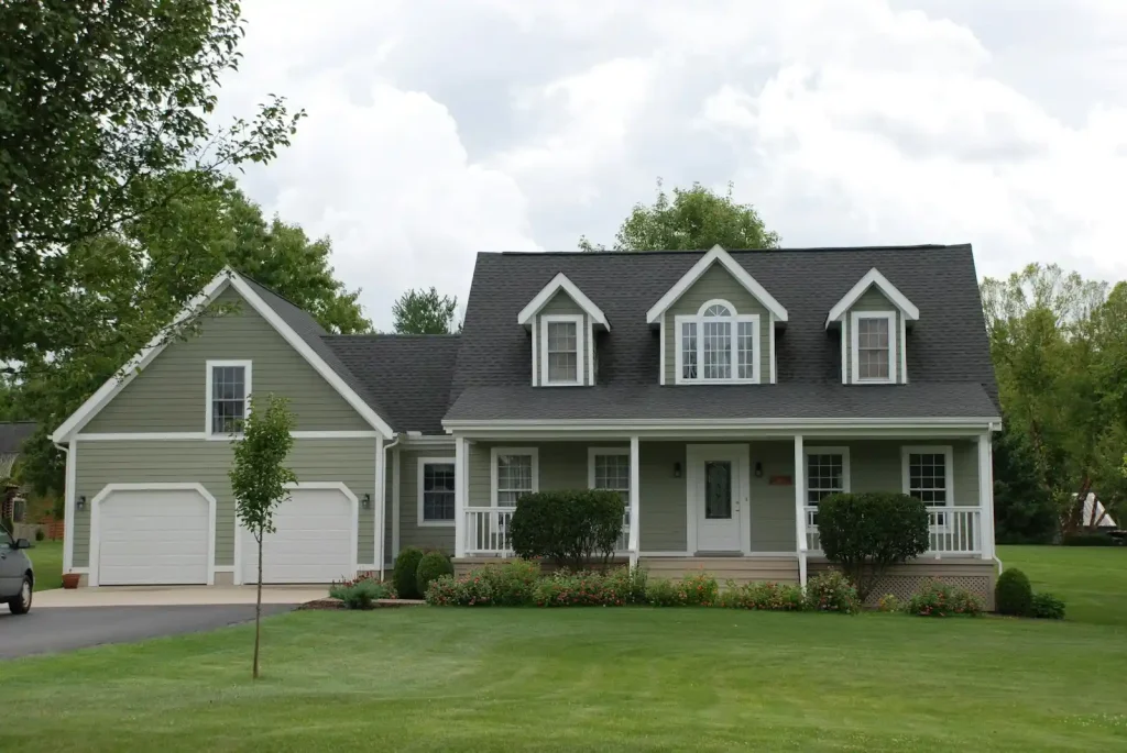 A clean white and gray house exterior beside a green lawn after house washing
