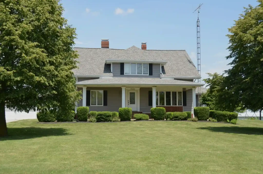 A traditional grey suburban house with a porch and green lawn in Fishers, Indiana