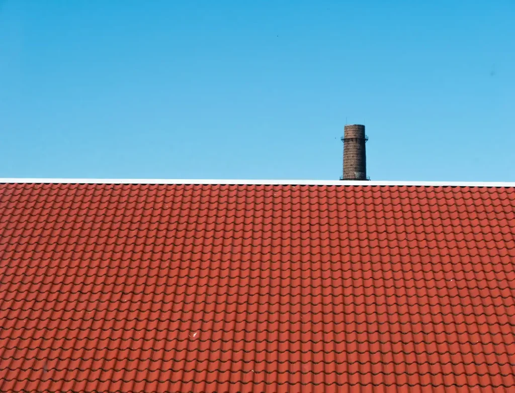 A clean asphalt shingle roof against a clear blue sky after professional roof soft washing