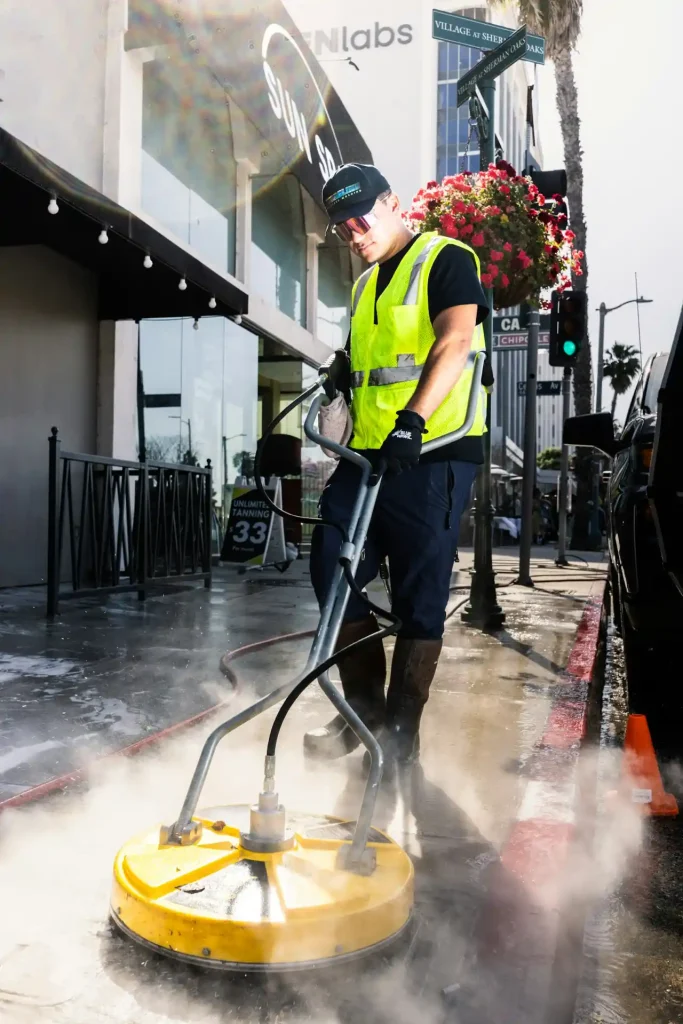 Crew member pressure washing a paved sidewalk surface in Indianapolis