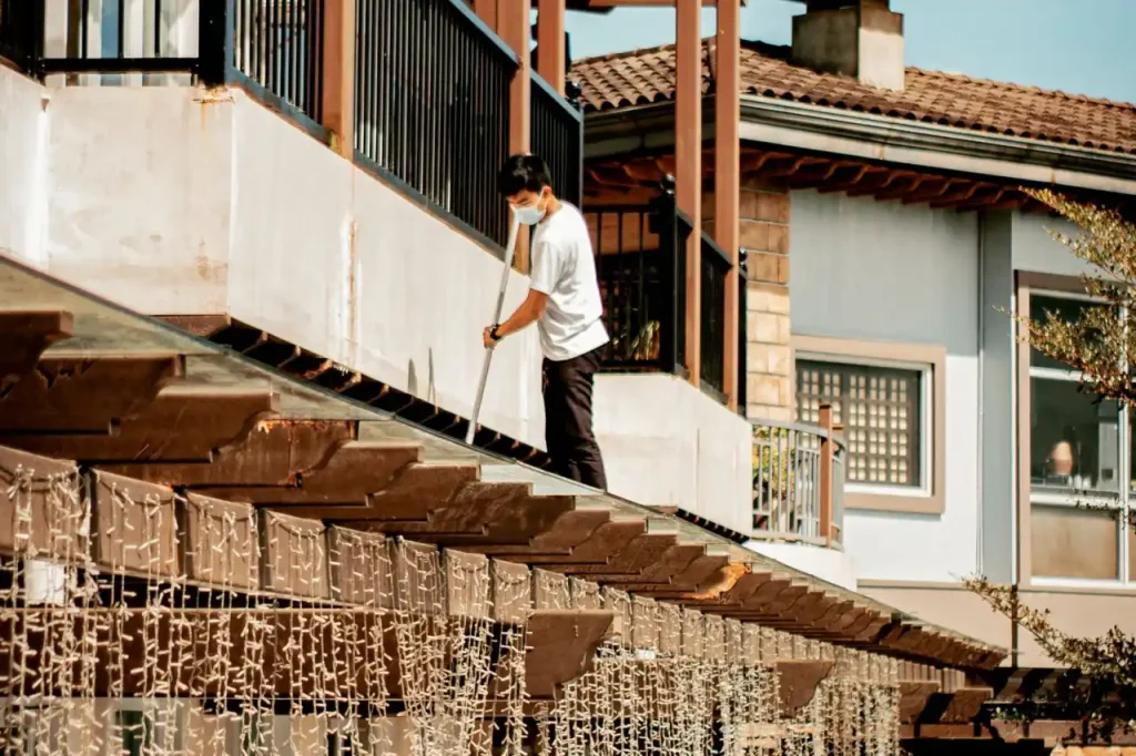 Cleaner sweeping the roof of a residential building