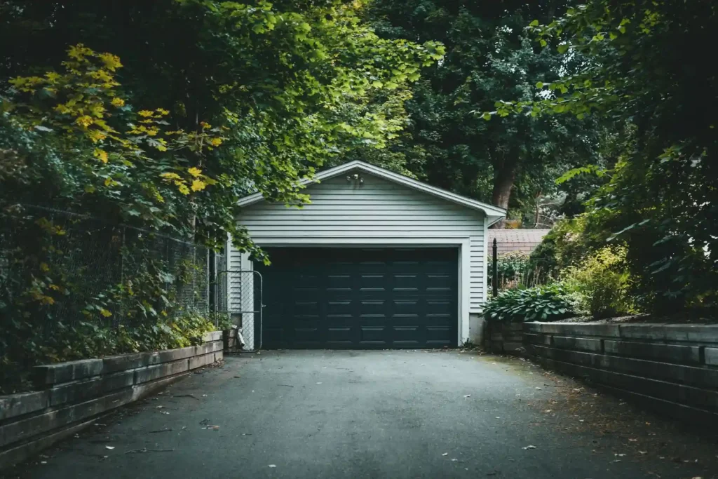 Detached garage with a driveway and greenery