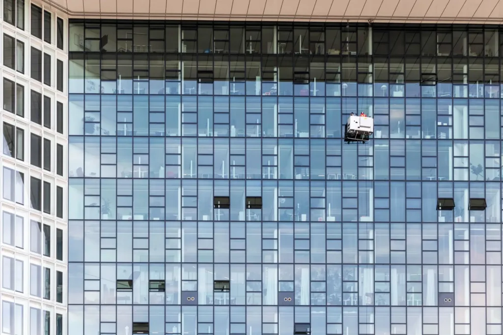 High rise glass building with window cleaners at work