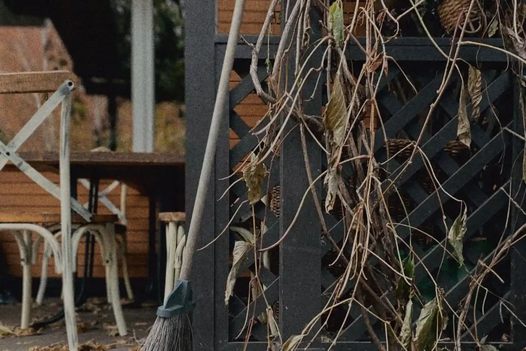 Patio with a broom and fallen leaves before cleaning
