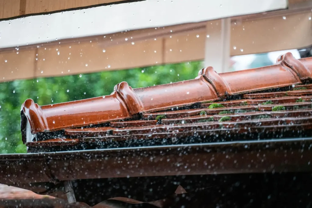 Rain droplets falling from a terracotta roof
