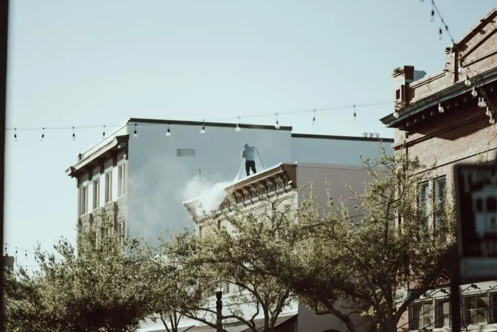 Rooftop worker using a pressure washer