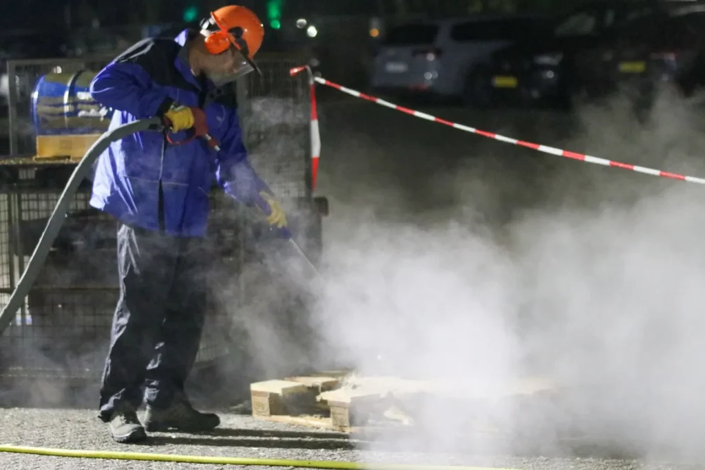 Technician in protective gear using a high pressure washer