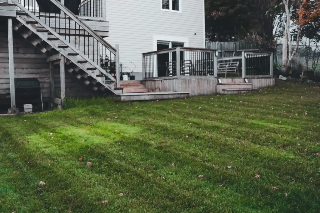 White house with a wooden deck and lawn