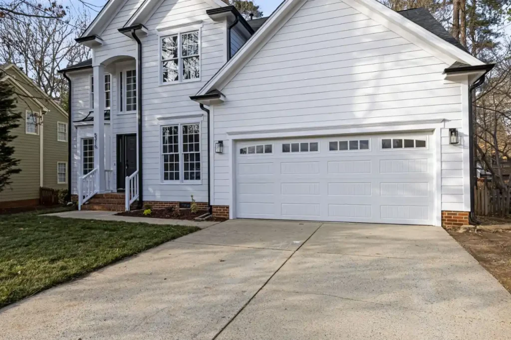 White wooden house with a garage in a suburban setting