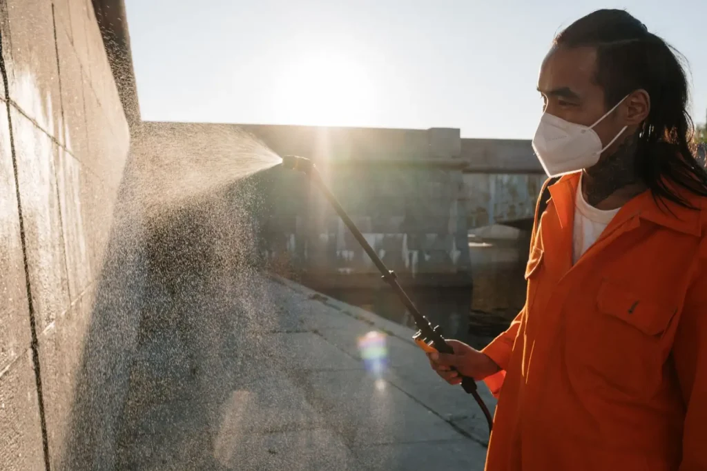 Worker in uniform spraying water onto an exterior wall