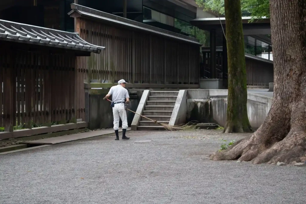 Worker sweeping an outdoor area beside a building