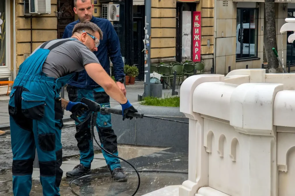 Workers cleaning a stone fountain with a pressure washer