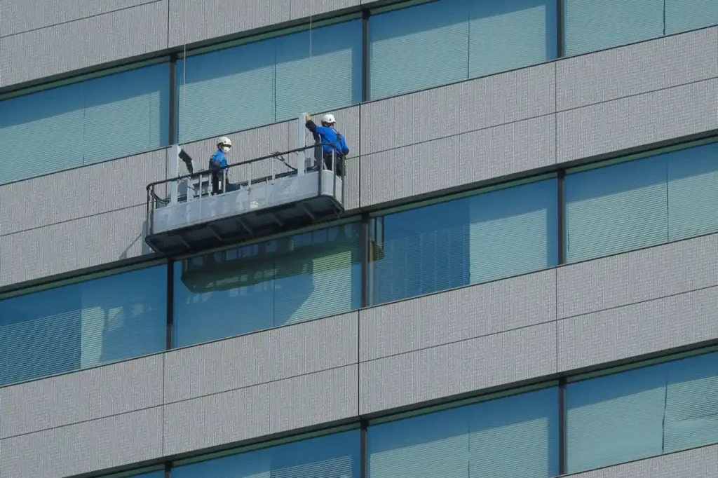 Workers cleaning windows on a glass building from a platform
